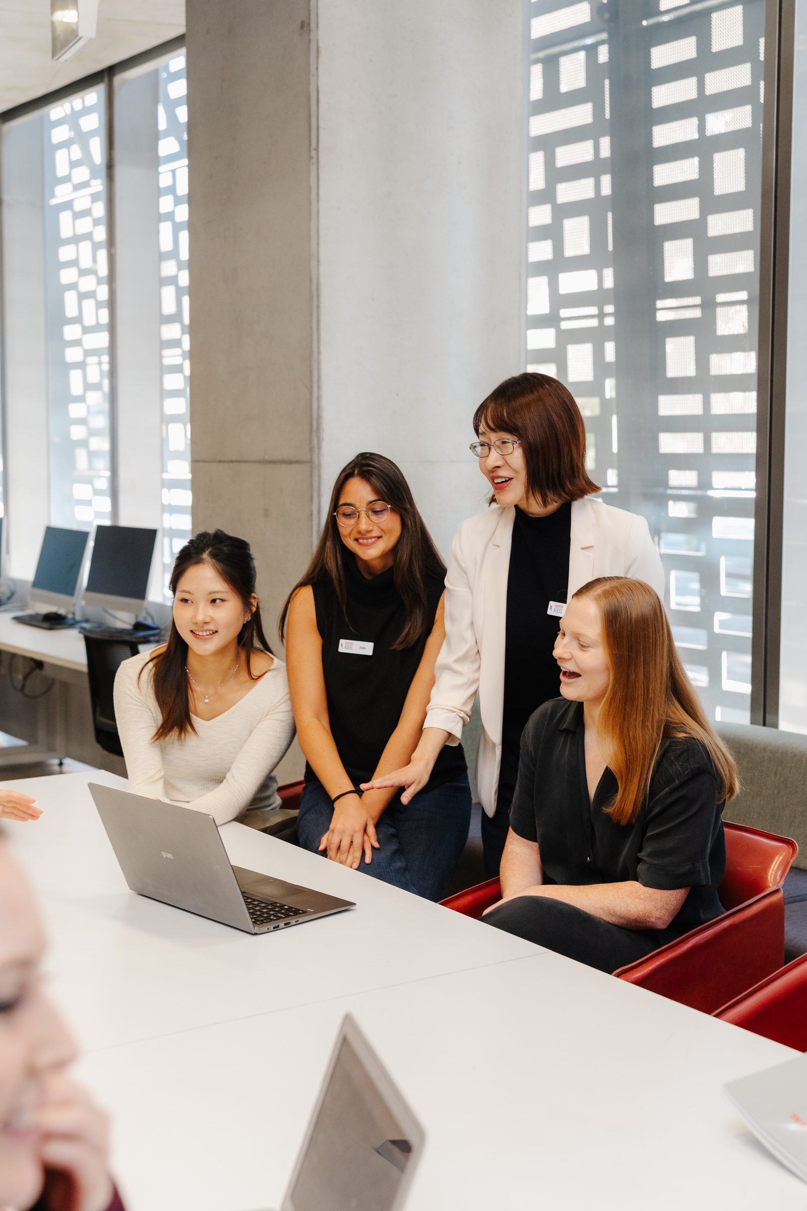 A small group smiling together around a laptop